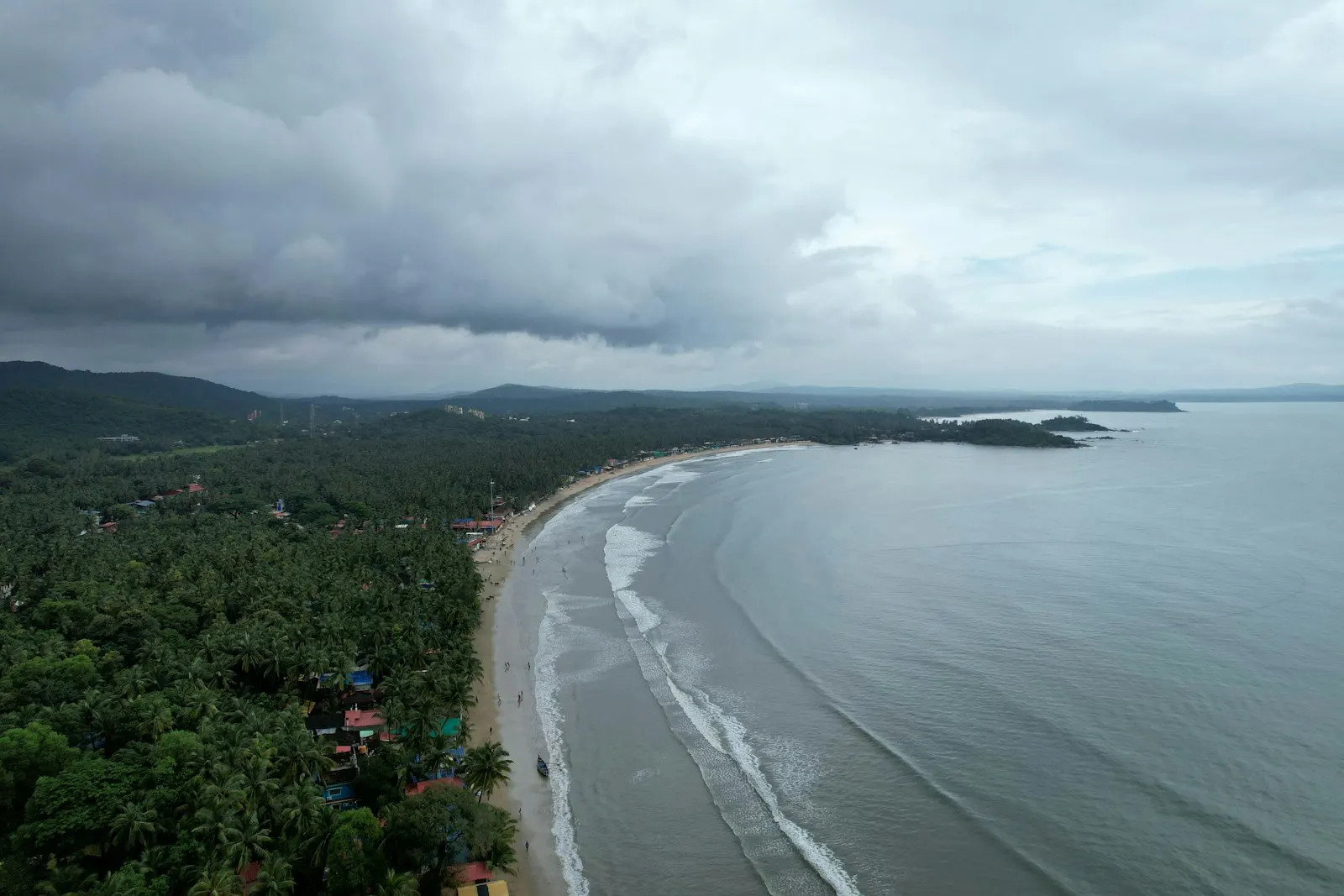 An aerial view of a beach and the ocean Palolem Beach is a stretch of white sand on a bay in Goa, South India. It's known for its calm waters. Lined with palm t