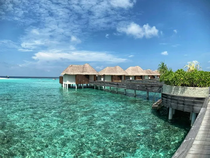 Brown wooden house on body of water under blue sky during daytime Overwater Villa at the W Hotel luxury resort in the Maldives: Maldives holiday packages by OYG
