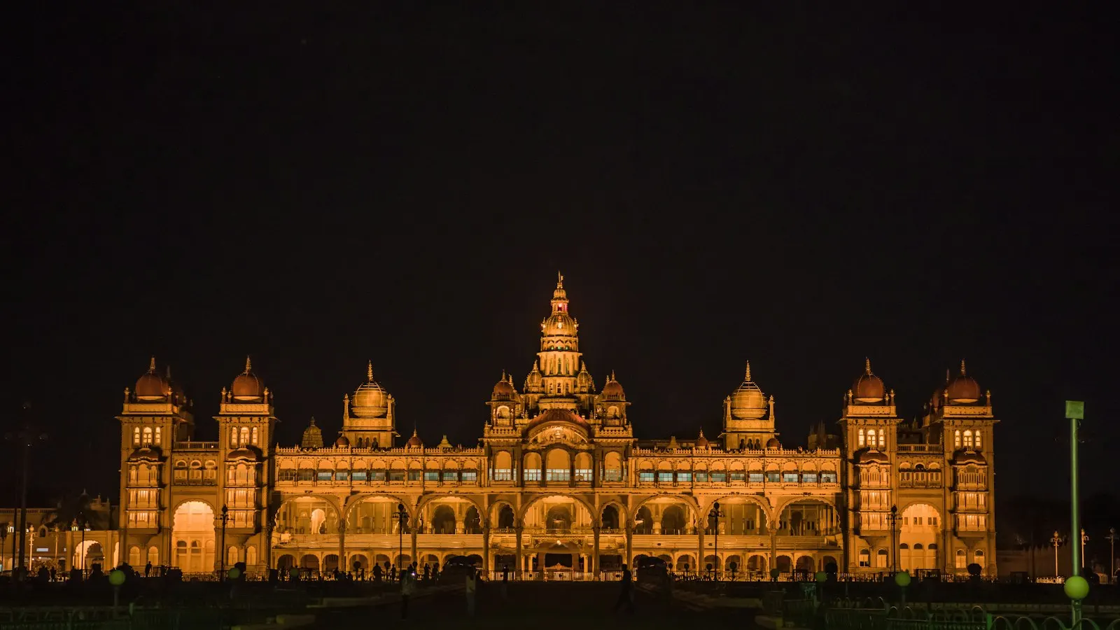Mysore Palace illuminated with warm golden lights against a dark night sky: Mysore holiday packages by OYG Holidays