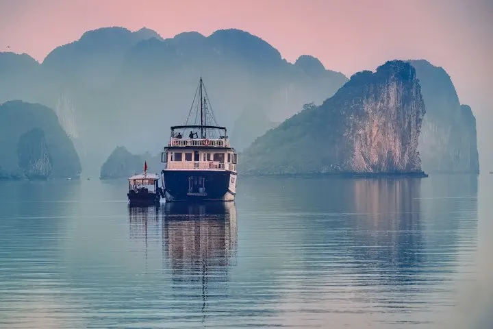 White and black boat on water near mountain during daytime: Vietnam holiday packages by OYG Holidays