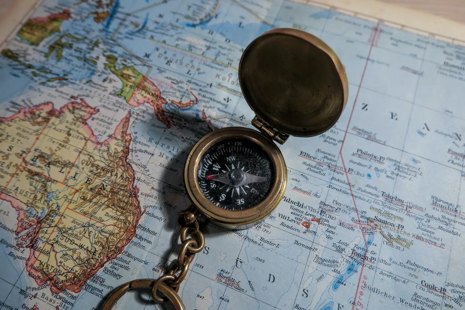 Round brass-colored compass on map: OYG Holidays, personalised holiday planners